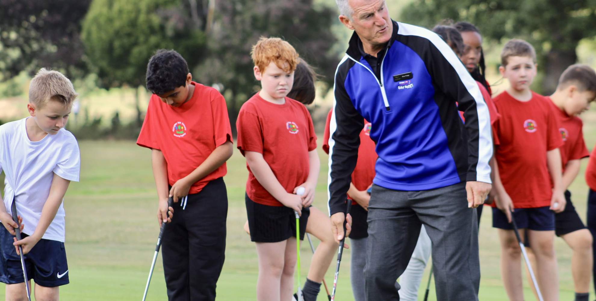 An image of a golf professional coaching junior players